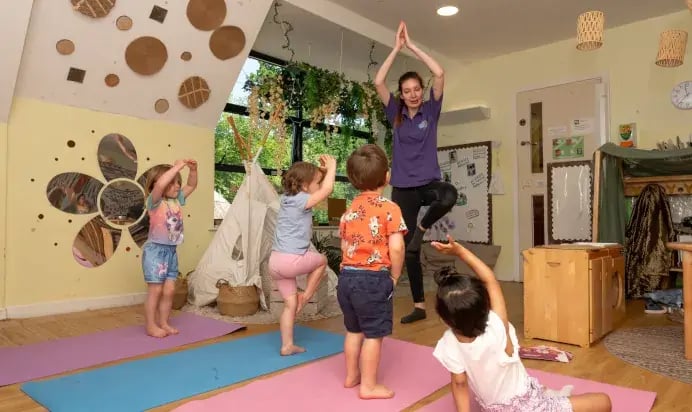 201910-children-doing-yoga-poses-with-key-worker-at-kiddi-caru-day-nursery-preschool-whiteley-692x412-1