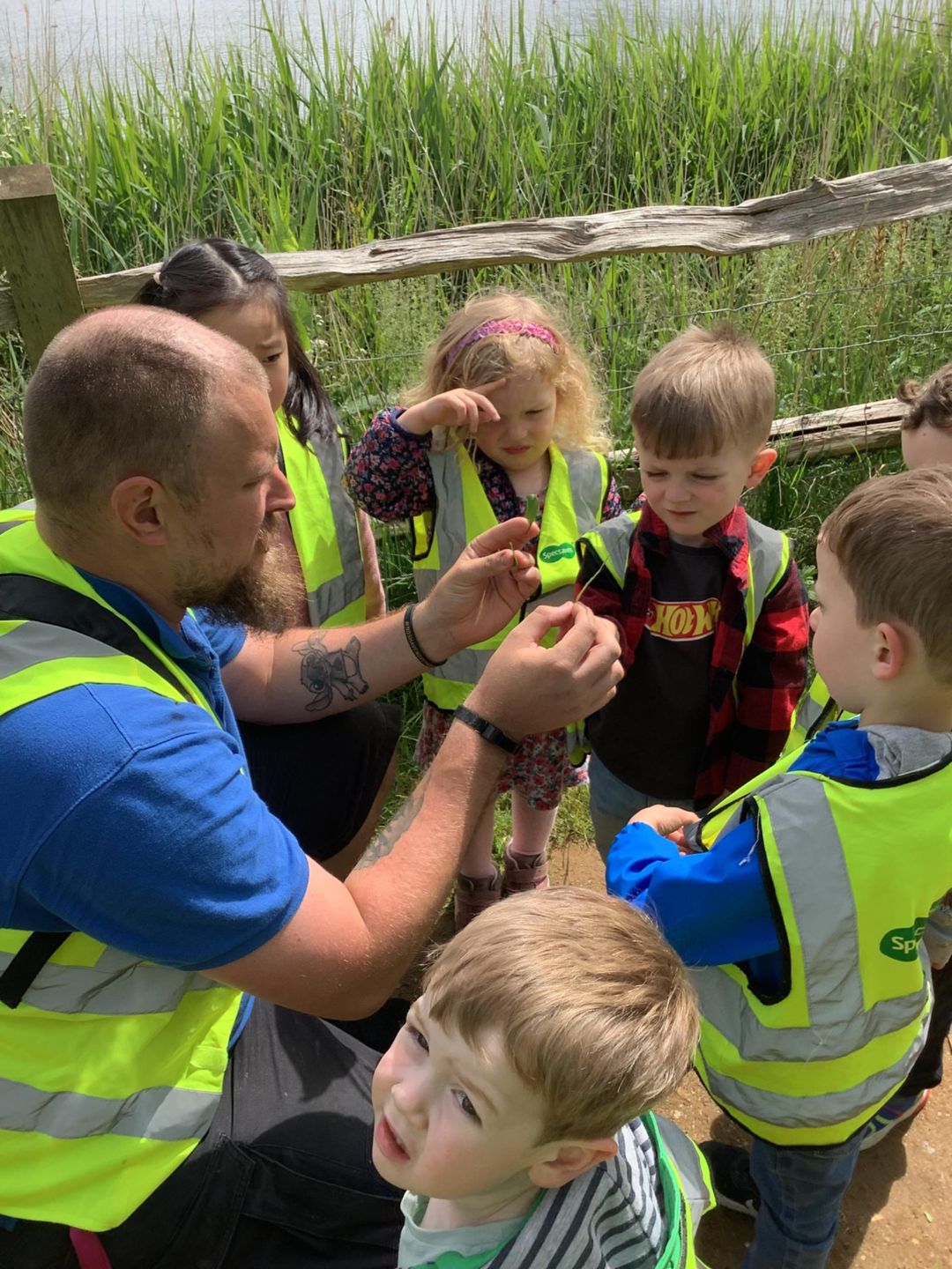 Male Nursery Practitioner with Early Years Children doing an outdoor learning activity.
