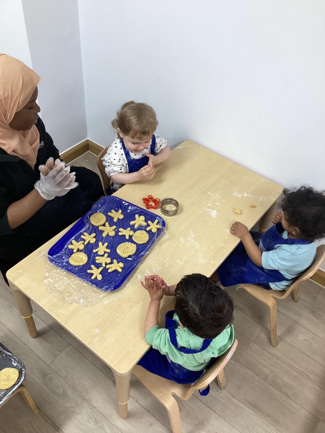 Children and a Nursery Practitioner at Kiddi Caru Day Nursery & Preschool at Great Park Road, Bradley Stoke, Bristol taking part in a baking activity.