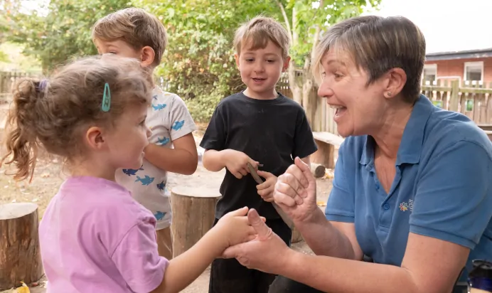 Child and key worker smiling together at The Kiddi Caru Day Nursery Preschool Writtle