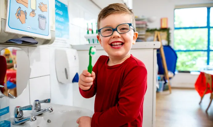 Child brushing their teeth smiling at Kiddi Caru Day Nursery Preschool Plympton Plymouth