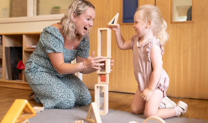 Child building wooden tower at The Kiddi Caru Day Nursery Preschool Writtle