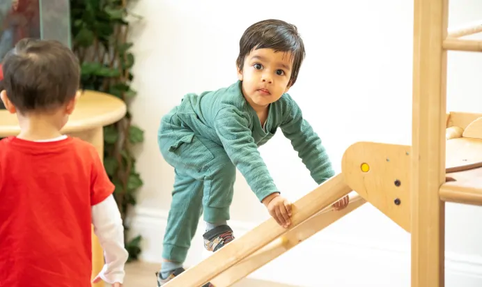 Child climbing wooden ladder on climbing frame at Little Acorns Day Nursery Preschool Stoneygate