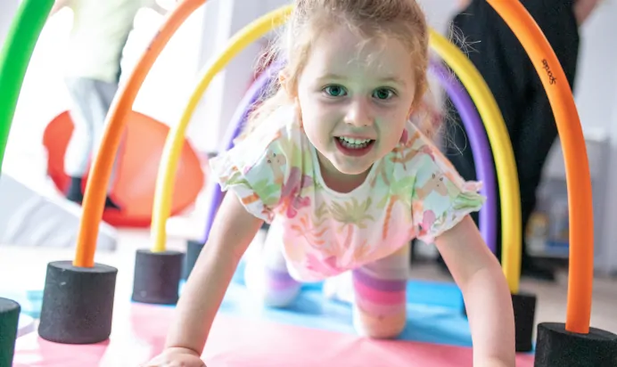 Child crawling through rainbow hoops at Charnwood Day Nursery Preschool Shepshed Loughborough