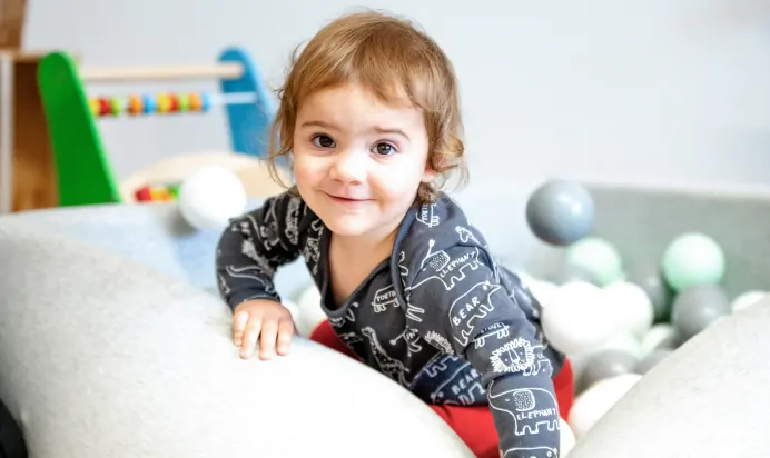 Child in a ball pit smiling to a camera at Charnwood Day Nursery Preschool Shepshed Loughborough