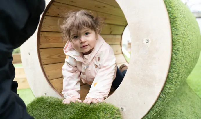 Child in grass tunnel at The Melton Mowbray Day Nursery Preschool Leicester