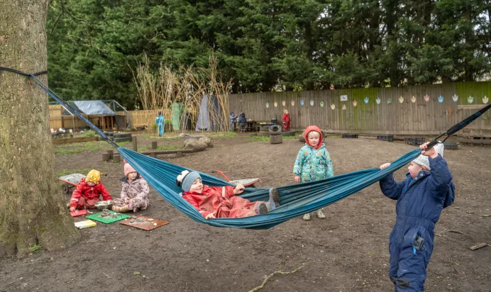Child laying in hammock outside at The Melton Mowbray Day Nursery Preschool Leicester