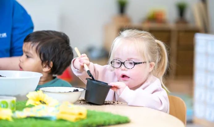 Child planting sunflower seeds with other children at Little Acorns Day Nursery Preschool Stoneygate