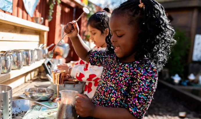 Child playing in the nature area with dirt and seeds at Kiddi Caru Day Nursery Preschool Caldecotte Milton Keynes