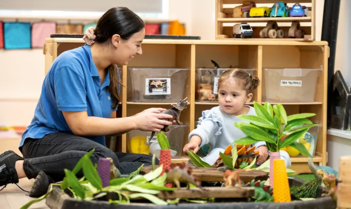 Child playing with dinosaurs and key worker at Charnwood Day Nursery Preschool Shepshed Loughborough