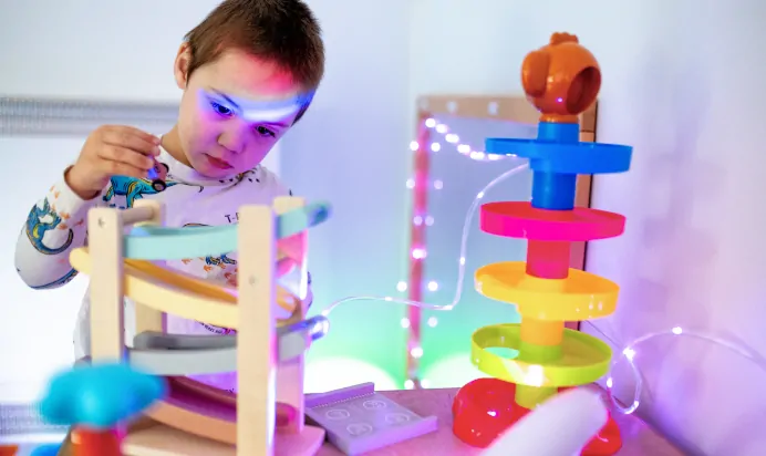 Child playing with wooden car with led lights in the background at Charnwood Day Nursery Preschool Shepshed Loughborough
