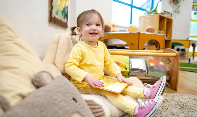 Child sitting on bean bag reading at Kiddi Caru Day Nursery Preschool Plympton Plymouth