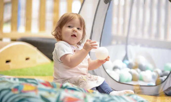 Child smiling in ball pit at The Kiddi Caru Day Nursery Preschool Burgess Hill