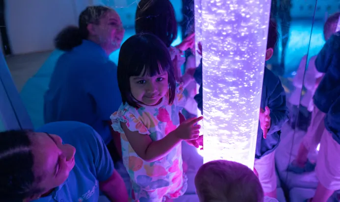 Child smiling in colourful interactive space at The Kiddi Caru Day Nursery Preschool Grange Park