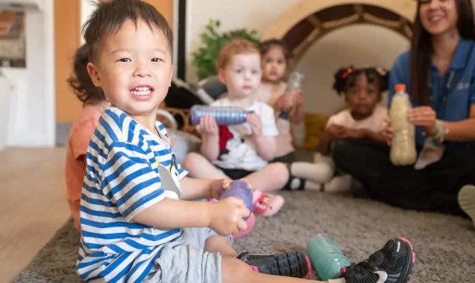 Child smiling with bottle at Kiddi Caru Day Nursery Preschool Walnut Tree Milton Keynes