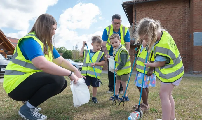Children and key worker litter picking in high vis jackets at Kiddi Caru Day Nursery Preschool Walnut Tree Milton Keynes