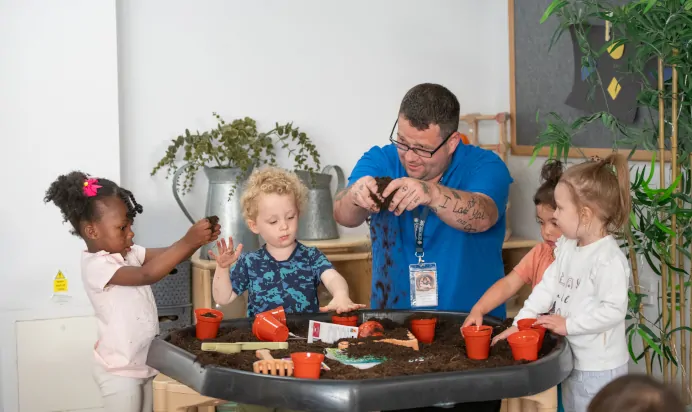 Children and key worker planting seeds at Kiddi Caru Day Nursery Preschool Walnut Tree Milton Keynes