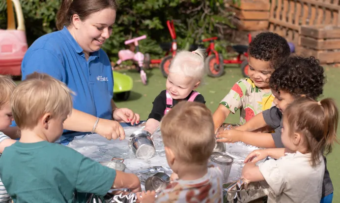 Children and key worker playing in water pit at The Kiddi Caru Day Nursery Preschool Writtle