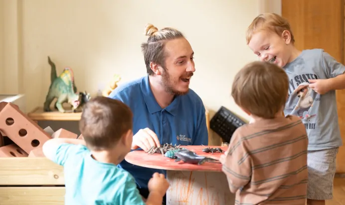 Children and key worker playing with dinosaurs at The Kiddi Caru Day Nursery Preschool Writtle