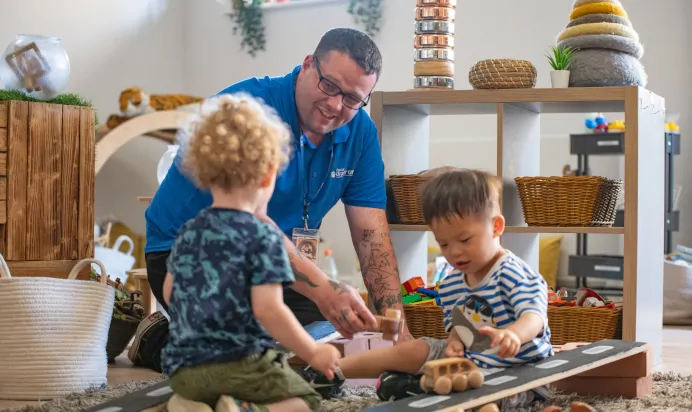 Children and key worker playing with wooden cars at Kiddi Caru Day Nursery Preschool Walnut Tree Milton Keynes