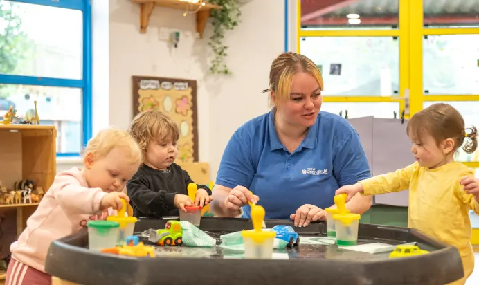 Children and key worker pretending to clean toy cars at Kiddi Caru Day Nursery Preschool Plympton Plymouth