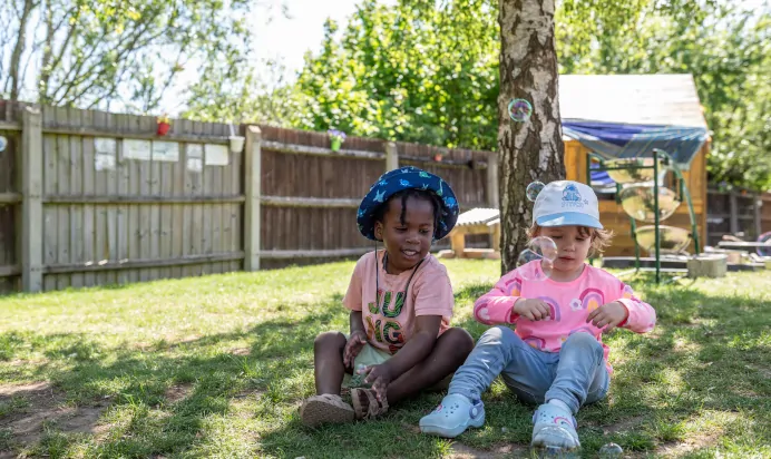 Children blowing bubbles outside at Kiddi Caru Day Nursery Preschool Wellingborough