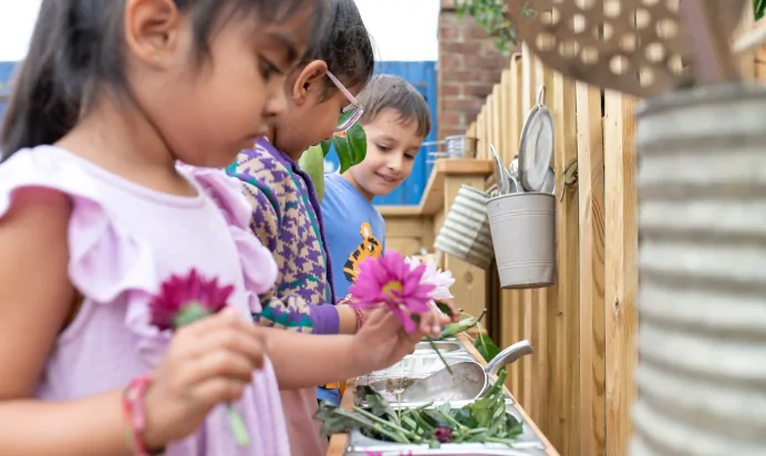 Children collaborating in outside space at The Kiddi Caru Day Nursery Preschool Grange Park