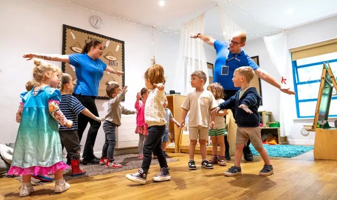 Children dancing with key workers in bright space at Kiddi Caru Day Nursery Preschool Torquay