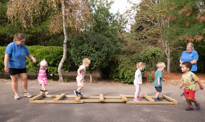 Children doing wooden obstacle course at The Kiddi Caru Day Nursery Preschool Writtle
