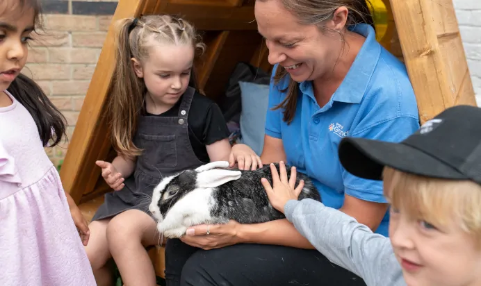 Children feeling a rabbit with key worker at The Kiddi Caru Day Nursery Preschool Grange Park