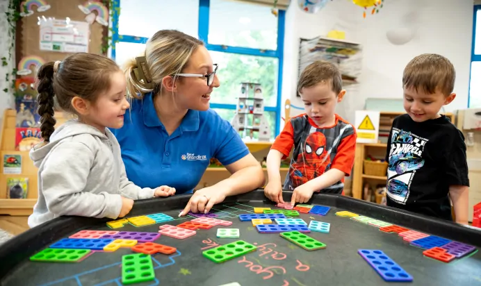 Children learning whilst playing game with key worker at Kiddi Caru Day Nursery Preschool Plympton Plymouth