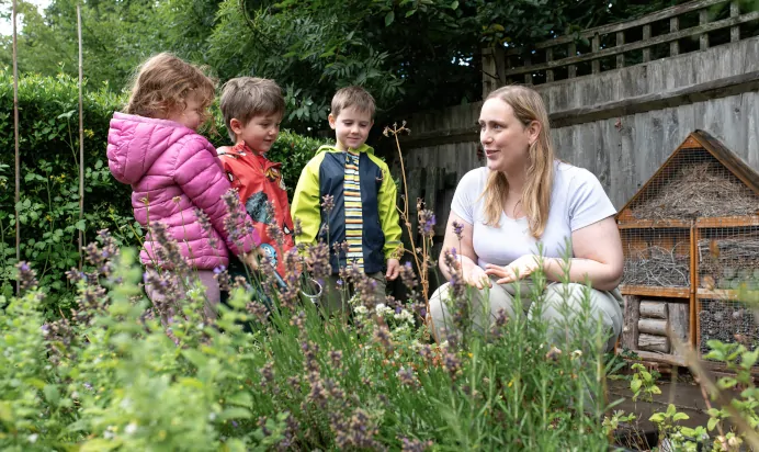 Children learning with key worker in outside space at The Kiddi Caru Day Nursery Preschool Burgess Hill