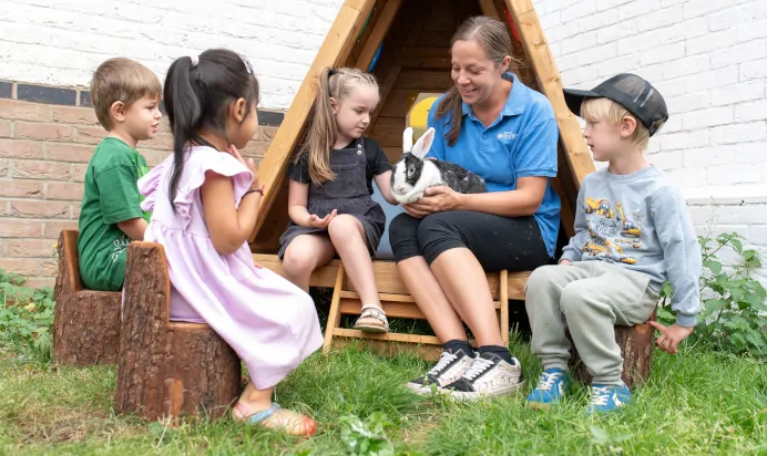 Children looking towards a rabbit with key worker at The Kiddi Caru Day Nursery Preschool Grange Park