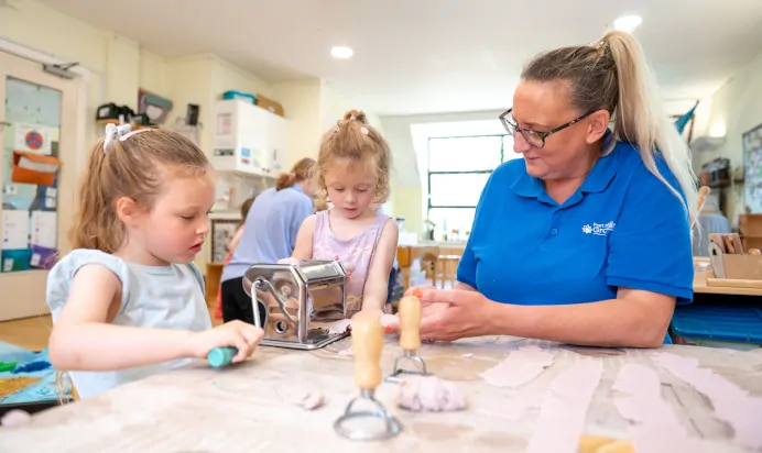 Children making clay models with key worker at Kiddi Caru Day Nursery Preschool Whiteley