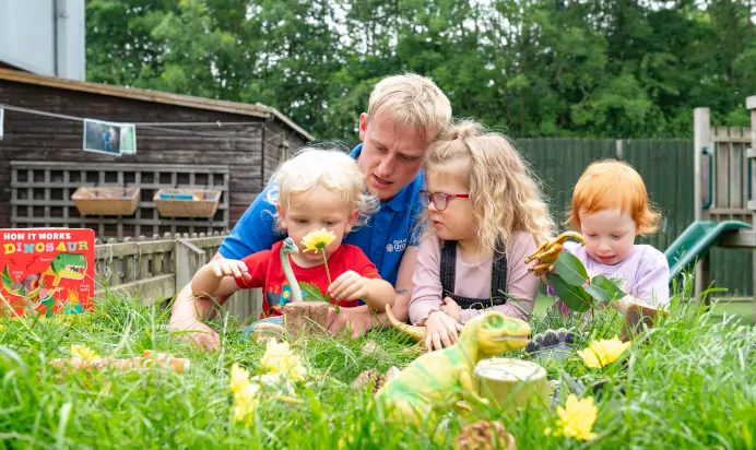 Children outside looking at flowers with key worker at Kiddi Caru Day Nursery Preschool Market Harborough