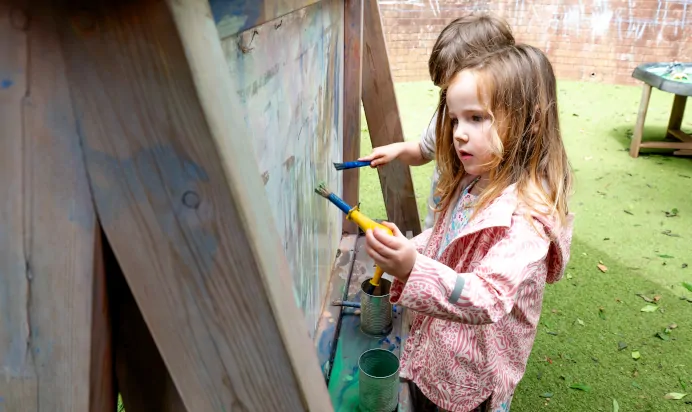 Children painting in a bright outdoor space at Kiddi Caru Day Nursery Preschool Torquay
