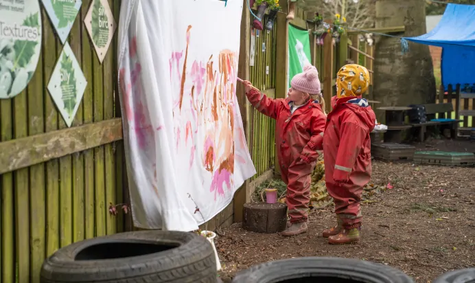 Children painting on sheet at The Melton Mowbray Day Nursery Preschool Leicester