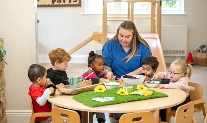 Children planting sunflower seeds with key worker at Little Acorns Day Nursery Preschool Stoneygate