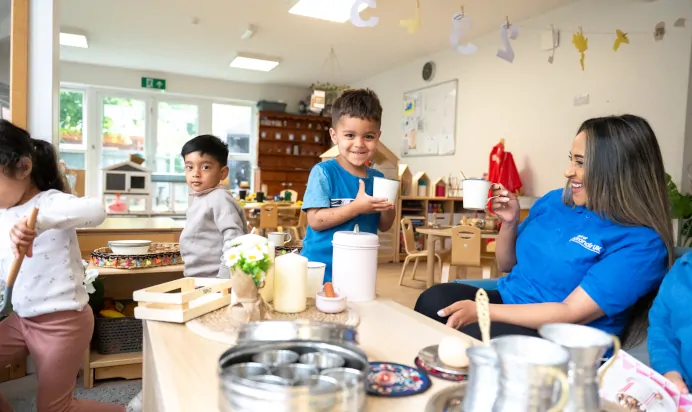 Children playing in play kitchen with key worker at Little Acorns Day Nursery Preschool Stoneygate