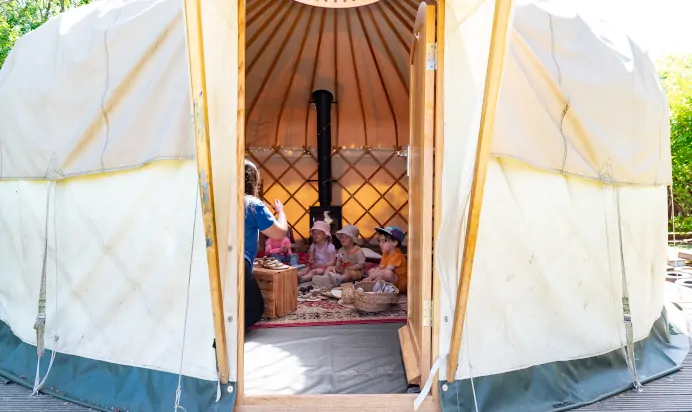 Children playing inside canvas tent with key worker at Kiddi Caru Day Nursery Preschool Wellingborough