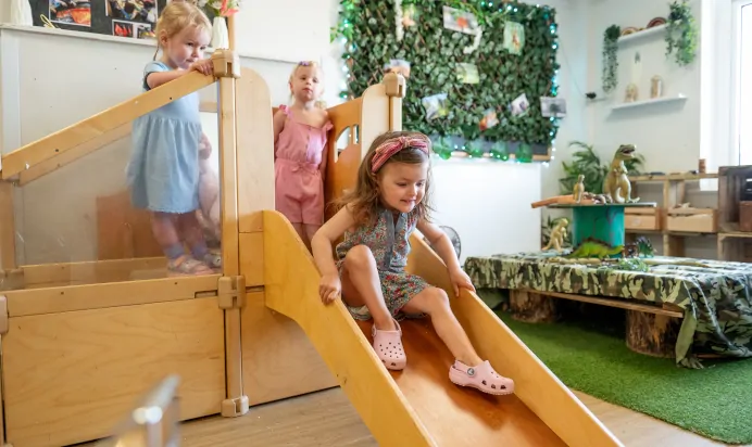 Children playing inside on wooden slide at Kiddi Caru Day Nursery Preschool Abington Park Northampton