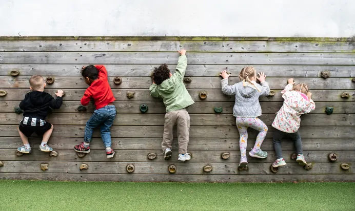 Children playing on climbing wall at Kiddi Caru Day Nursery Preschool Peterborough