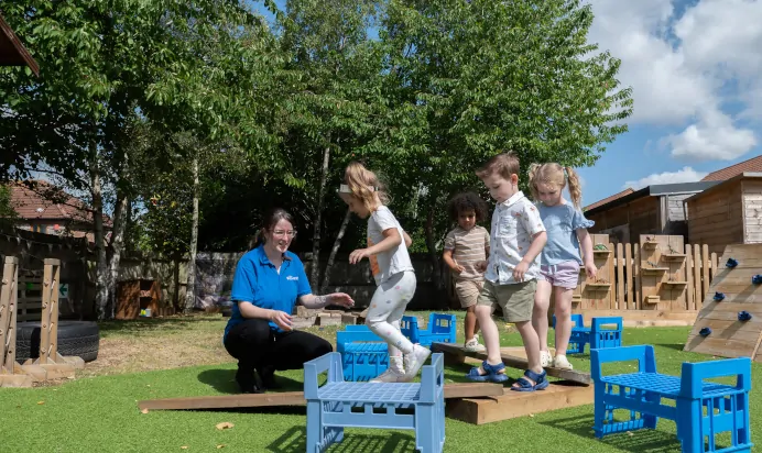 Children playing on obstacle course with key worker at Kiddi Caru Day Nursery Preschool Walnut Tree Milton Keynes