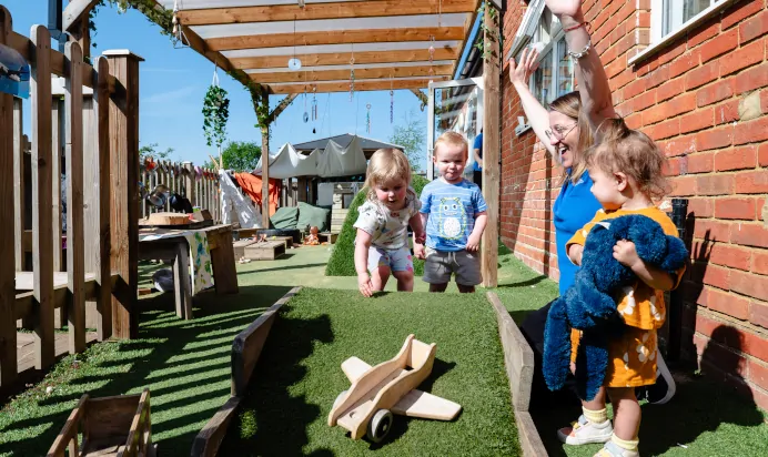 Children playing outside with key worker at Kiddi Caru Day Nursery Preschool Leighton Buzzard
