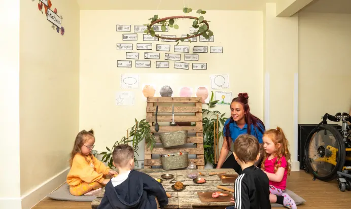 Children playing with fake food and key worker at The Laurels Day Nursery Preschool Queniborough