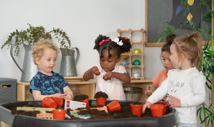 Children playing with soil at Kiddi Caru Day Nursery Preschool Walnut Tree Milton Keynes