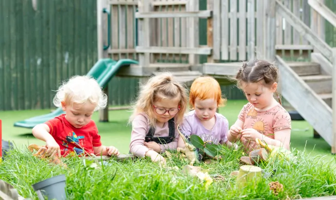 Children playing with toys in the grass at Kiddi Caru Day Nursery Preschool Market Harborough