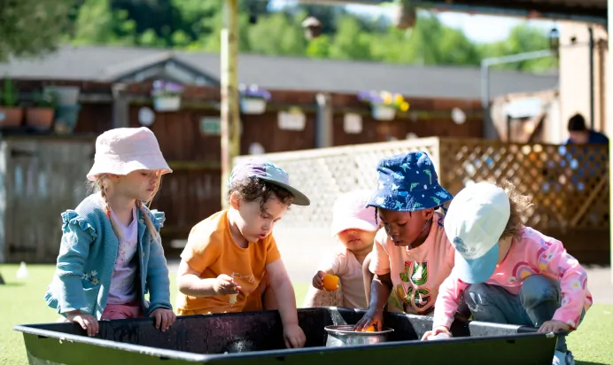 Children playing with water outside at Kiddi Caru Day Nursery Preschool Wellingborough
