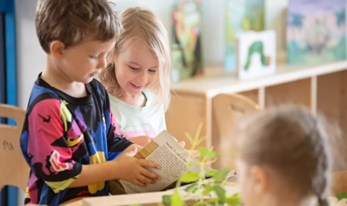 Children reading a book together at The Kiddi Caru Day Nursery Preschool Taunton
