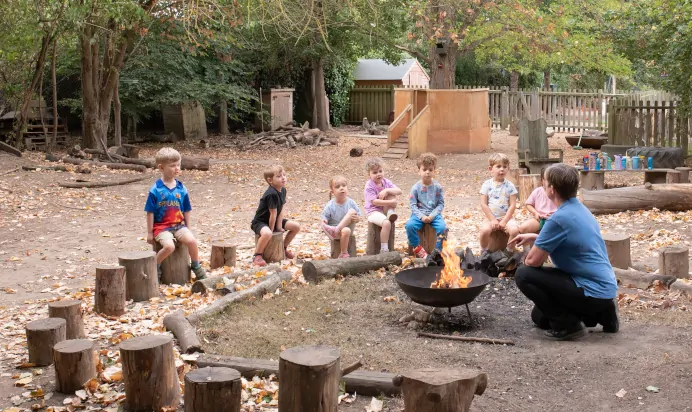Children sitting around campfire at The Kiddi Caru Day Nursery Preschool Writtle